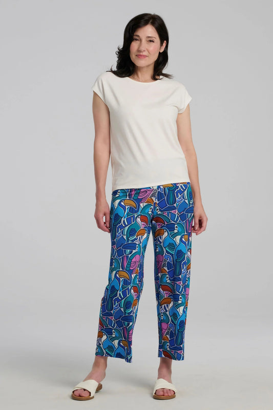 A woman wearing the Eowyn T-Shirt by Kollontai in Off White with patterned capri pants standing against a grey background. 