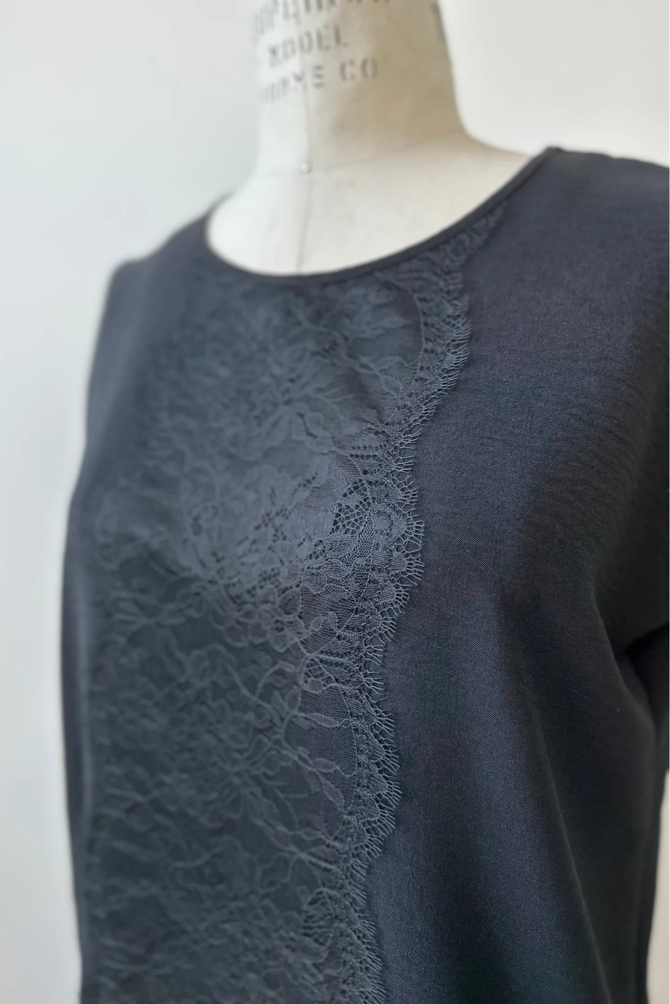 A close up detail of the lace applique on the Pearl T-shirt by Kollontai in Black is shown on a mannequin. 