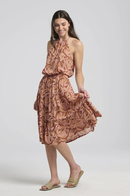 A woman wearing the Al-Uzza Skirt by Kollontai in Cinnamon print, a tiered skirt with an elastic waist and a below-the-knee length, with the matching Semira Camisole, standing in front of a white background 