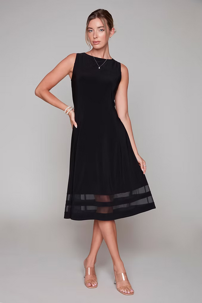 A woman wearing the Rowena Dress by Compli K, a sleeveless black dress with a cocktail length hem with sheer bands across it. 