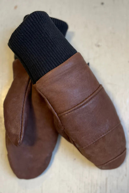 A pair of brown Lhasa mittens with ribbed cuffs, made from recycled leather, and lined with fleece.