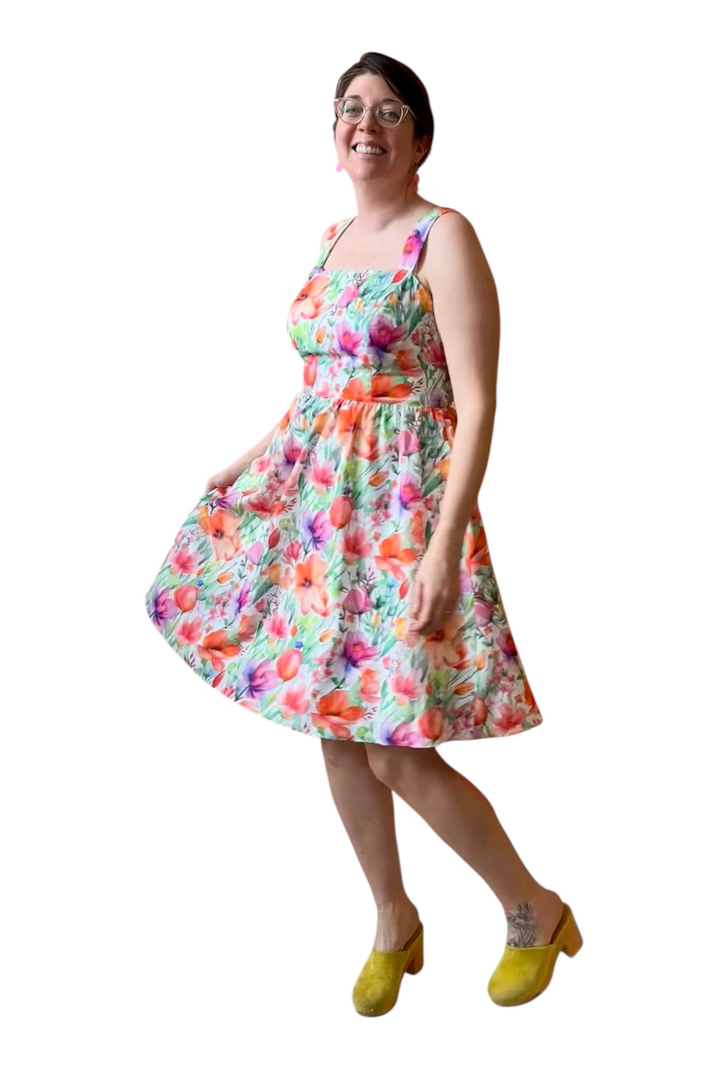 A woman wearing the Rue Floral Dress by Compli K, a midi-length tank dress with wide straps, a square neckline, a gathered waist and a full skirt. She is shown against a white background.