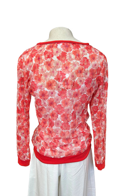 A back view of the Daisy Lace Shirt by Karkass in Coral, a floral lace shirt with solid cuffs and hem, is shown over a white tank and with white pants against a white background. 