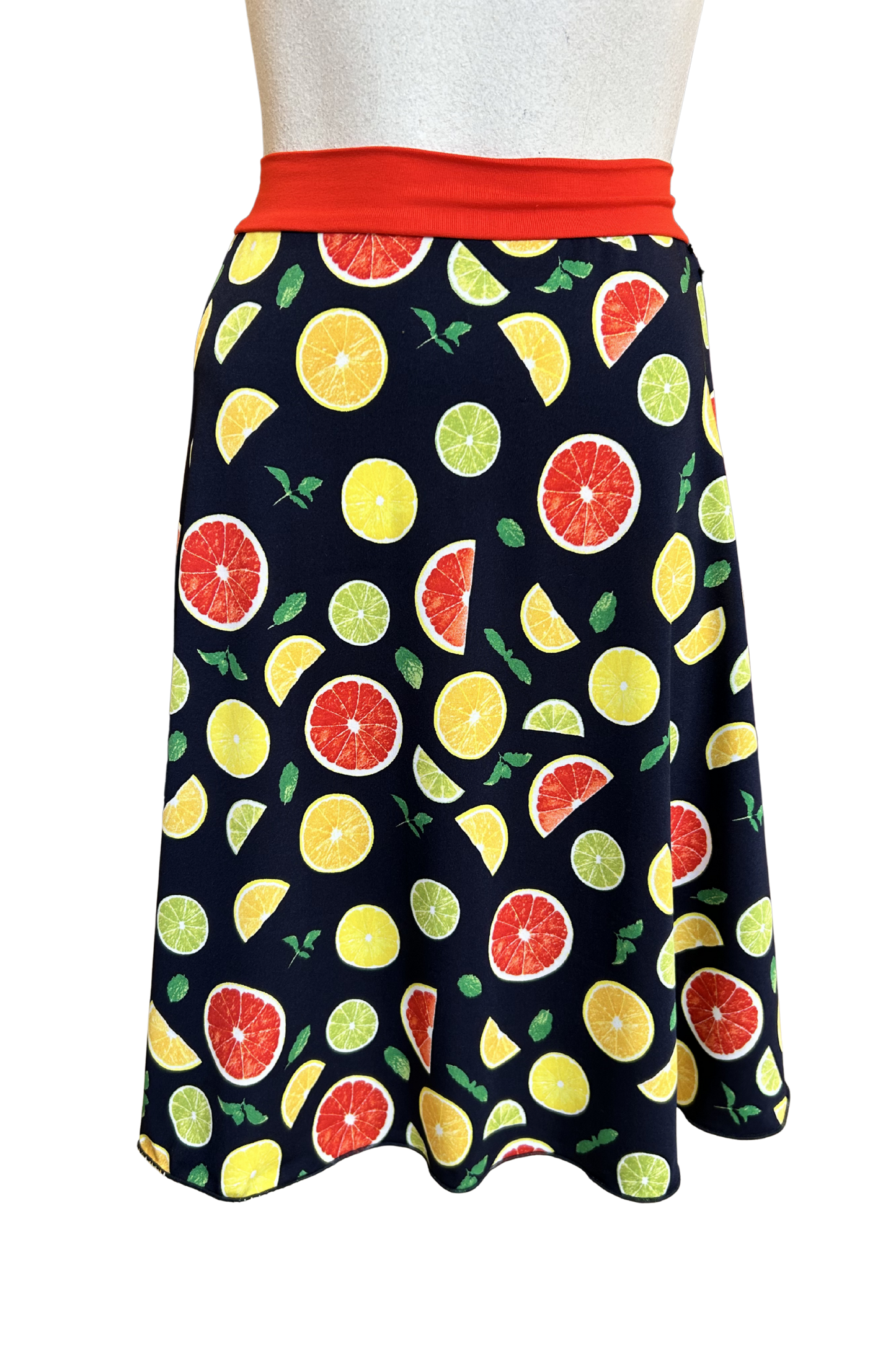 The Flirt Skirt by Slak in Citrus Print, an above the knee A-line skirt with a contrasting pull-on waistband, is shown on a mannequin against a white background. 