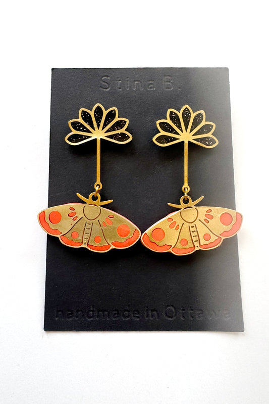 Pair of butterfly-shaped earrings on a black card with 'Stina B' branding.