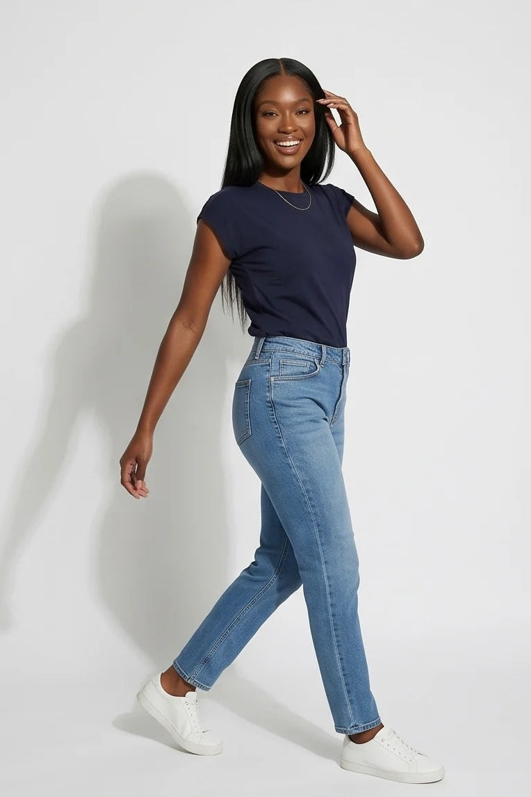 A woman wearing the Eowyn T-Shirt by Kollontai in Navy with jeans standing against a grey background. 
