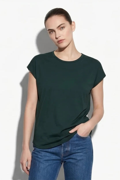A woman wearing the Eowyn T-Shirt by Kollontai in Green with jeans standing against a grey background. 