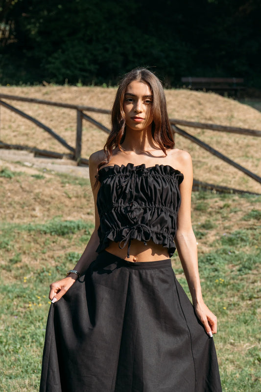 Woman wearing the Savannah maxi skirt from MAS in black and a ruched black tube top, standing outdoors.