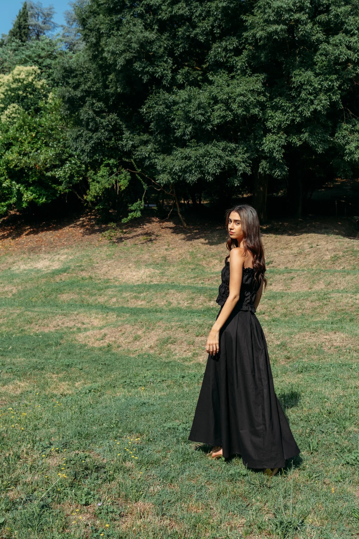 Woman wearing the Savannah maxi skirt from MAS in black and a ruched black tube top, standing outdoors.