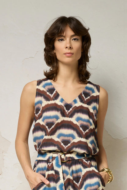 Hip-up view of a woman wearing the Sita Top by Cokluch in Feather print, a sleeveless V-neck tank with a loose fit and wide straps. She is wearing it with matching shorts against a plain background