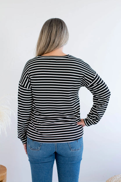 Back view of a woman wearing the Munro Bamboo Crewneck sweater by Ang Hill in black and white stripes. She is wearing it with jeans against a white background.