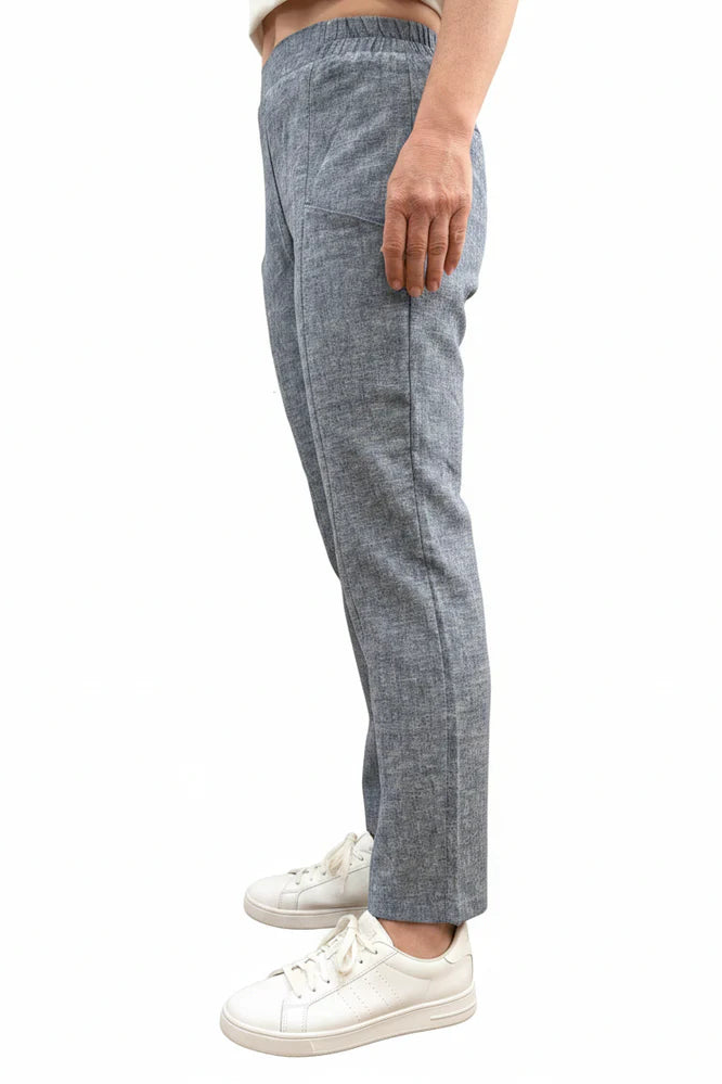 Side waist down view of a woman wearing the Cantley Short Pants by Message Factory in Natural Blue, slim cut capri pants with an elastic waist. She is standing in front of a plain background. 
