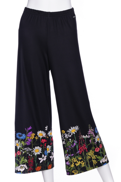 The Amaretto 7/8 Gaucho Pants from Rien ne se Perd in Black with a floral print hem are shown on a mannequin in front of a white background. 