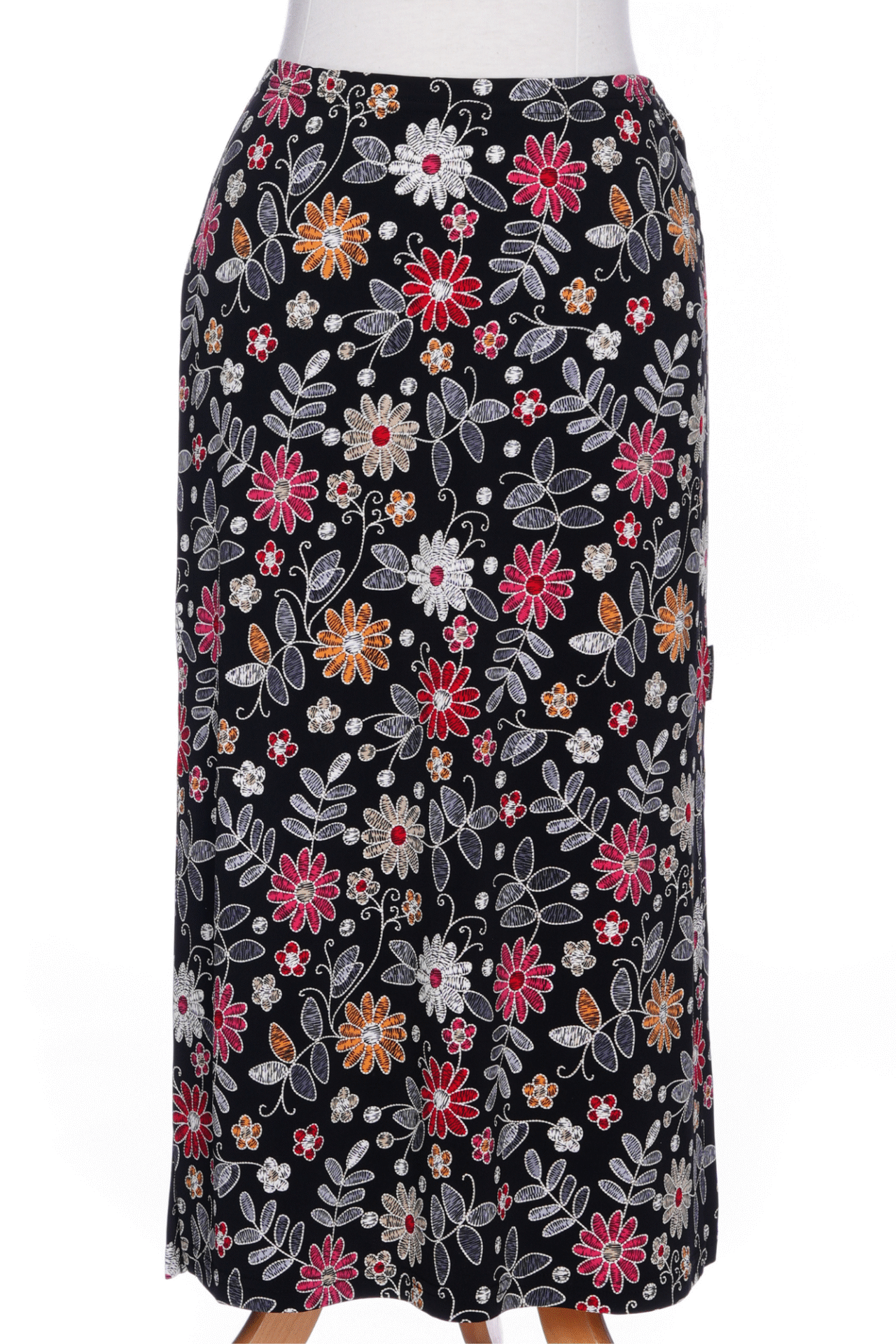 A back view of the Fiesta 7/8 Skirt by Rien ne se Perd in Colourful Daisies, a slightly A-line skirt with an elastic waist and side slits, is shown on a mannequin against a white background 