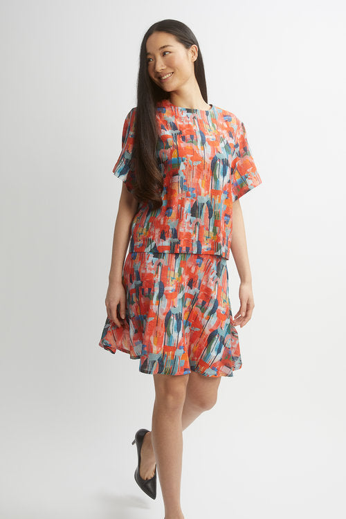 A woman wearing the Sauge Skirt by Dinh Ba in Red multicolour print, a short A-line skirt. She is wearing it with a matching top against a white background. 