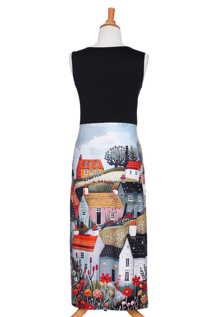 A back view of the Mimosa Dress by Rien ne se Perd in Black/Landscape print, a sleeveless 7/8 length dress with a solid black top and a straight skirt with a print of houses and flowers, is shown on a mannequin against a white background. 