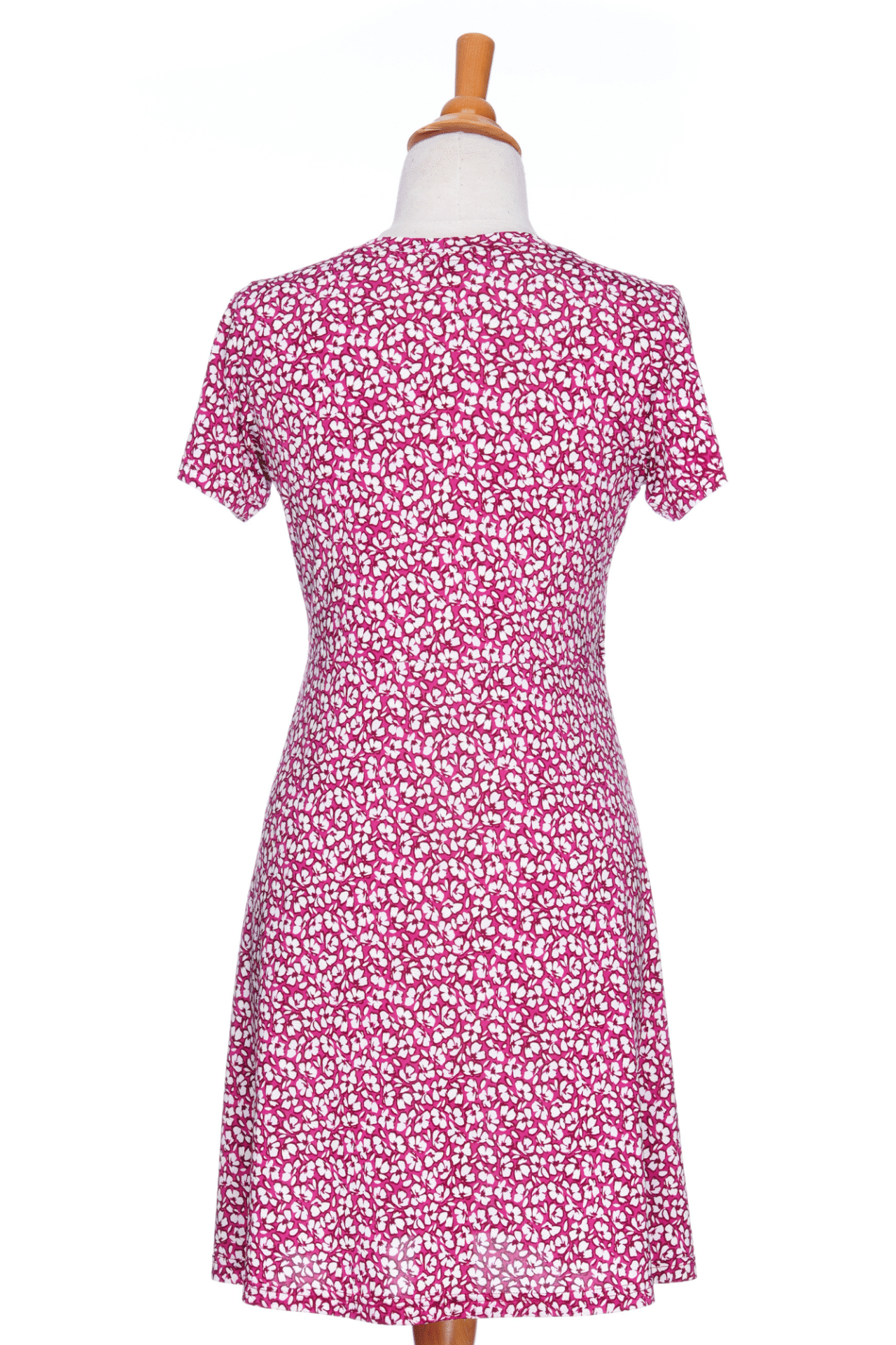  A back view of the Sangria Dress by Rien ne se Perd in Raspberry floral print, a short dress with a V-neck, an adjustable drawstring ribbon under the bust, and short sleeves, is shown on a mannequin against a white background. 