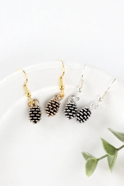 Pine cone earrings by Birch Jewellery; silver and gold; styled on a white ceramic dish